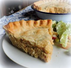 a piece of pie sitting on top of a white plate next to a bowl of salad