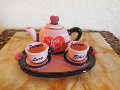 two cups and a teapot on a tray with the words i love you written on them