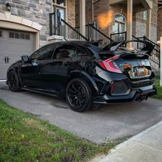 a black sports car parked in front of a house with stairs leading up to it