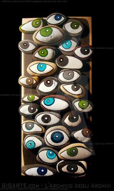 an artisticly designed wall hanging made out of ceramic and painted with blue, green and white eyes