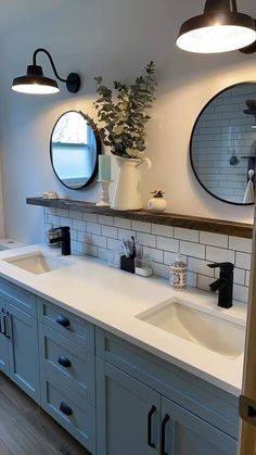 a bathroom with two sinks, mirrors and lights on the wall next to each other