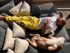 a man laying on top of a couch next to a dog