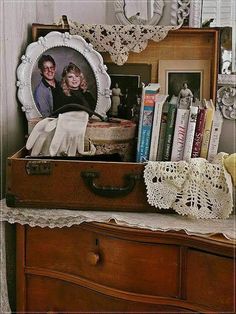 an old suitcase is sitting on a dresser with books and other items in front of it