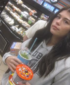 a woman holding a drink in front of a vending machine at a grocery store