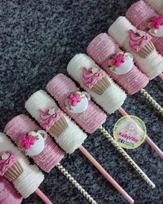 pink and white cupcakes are arranged on sticks