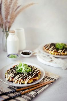 two white plates topped with food on top of a table next to some chopsticks