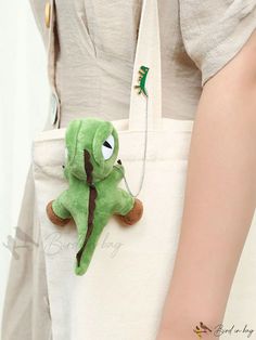 a person holding a bag with a stuffed animal in it's pocket and a keychain attached to the back