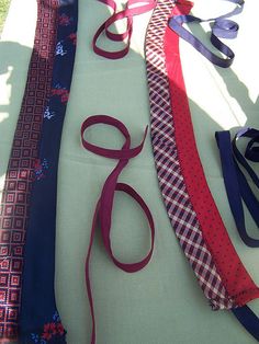 several ties laid out on a table with one tied up and the other untied