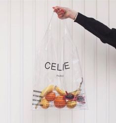 a person holding a clear plastic bag with fruit inside it and the word celie printed on it