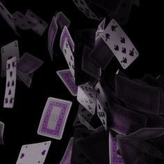 playing cards falling down into the air with purple ink on them and black paper underneath