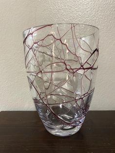 a clear glass with red lines on it sitting on top of a wooden table next to a white wall