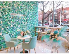 the interior of a restaurant with blue chairs and green flowers on the wall behind it