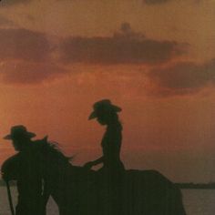 two people are riding horses in the water at sunset or dawn, with one person standing on top of another horse