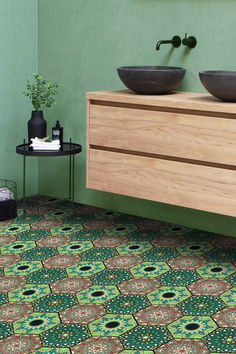 a bathroom with green walls and two sinks on the counter, next to a wooden cabinet