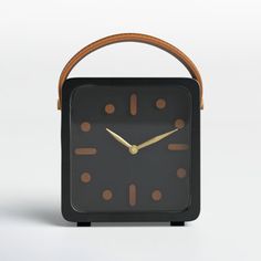 a black clock with brown numbers and a wooden handle on the front, against a white background