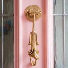 a gold door handle on a pink door