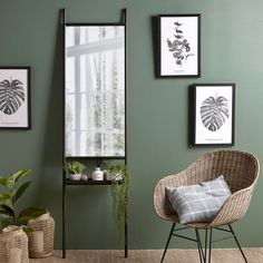 a living room with green walls and pictures on the wall, including a wicker chair