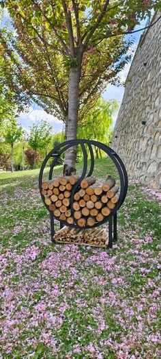 there is a bench made out of logs in the grass and flowers on the ground