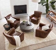 a living room with brown leather chairs and a round coffee table in front of a fireplace