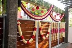 an outdoor wedding decorated with flowers and garlands on the fence, along with wooden slats