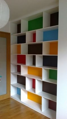 an empty room with colorful bookshelves on the wall and wood flooring in front of it