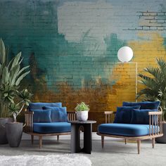 two chairs and a table in front of a brick wall with potted plants on it