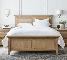 a bed with white linens and pillows in a large room next to two lamps