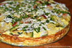 an omelet with cheese and herbs on top sits on a wooden table, ready to be eaten