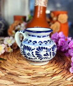 a blue and white vase sitting on top of a wicker basket next to flowers