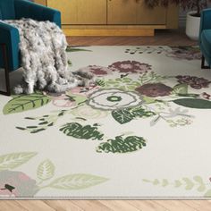 a living room with two blue chairs and a rug on the floor in front of it