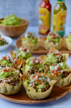 some taco cups are on a plate with guacamole in the background