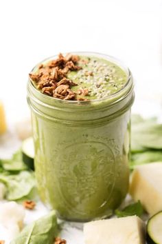 a green smoothie in a mason jar surrounded by sliced cucumbers