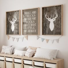 two framed deer head pictures hang on the wall above a bench with pillows and blankets