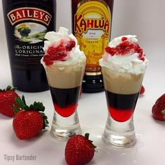 two glasses filled with ice cream and strawberries next to bottles of kahlua