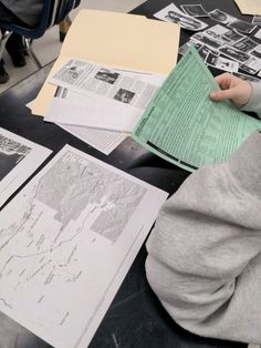 a person sitting at a table with some papers on it and one hand holding a piece of paper