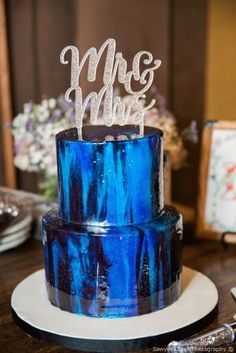 a blue wedding cake with the word mr and mrs on top is sitting on a table