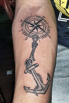 a man with a compass and anchor tattoo on his arm