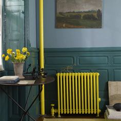 a yellow radiator in the corner of a room with books and vases