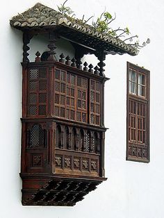 an old wooden window on the side of a white building with plants growing out of it