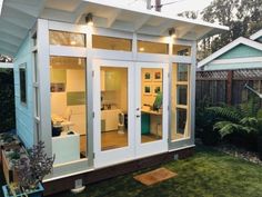 a small backyard shed with sliding glass doors on the front door and windows in the back