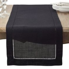 a black table runner on top of a wooden table with white plates and silverware