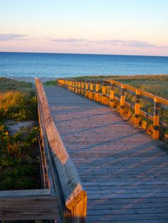 a wooden walkway leading to the beach at sunset