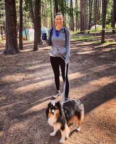 a woman is walking her dog in the woods