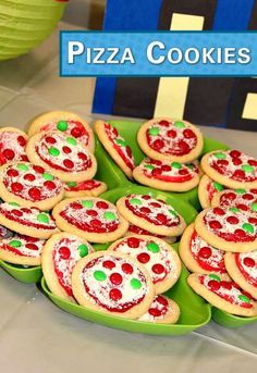 there are many pizza cookies on the green platter with red and green toppings