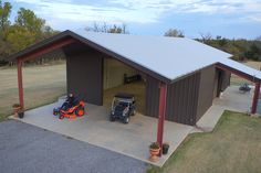 two lawn mowers are parked in front of a garage with an attached carport