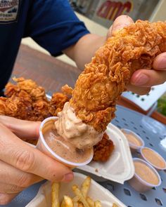 a person is holding food in their hand and dipping it into some kind of sauce