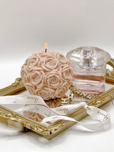 a candle that is sitting on some kind of tray with flowers in it and ribbon around the edge