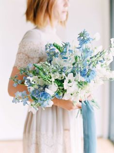 a woman holding a bouquet of blue and white flowers