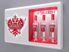 three bottles of smirnoff vodka are displayed in a display case on the wall