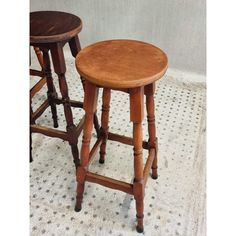 two wooden stools sitting next to each other on top of a white tile floor